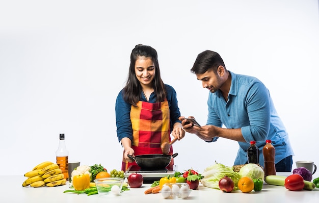 Indiaas koppel in de keuken - Jonge mooie Aziatische vrouw geniet van koken met man met veel verse groenten en fruit