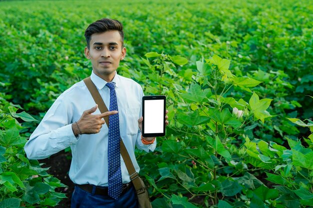 Foto agronomo o banchiere indiano che usa tablet o telefono sul campo agricolo