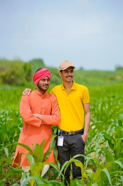 Indian agronomist with farmer at green agriculture field.