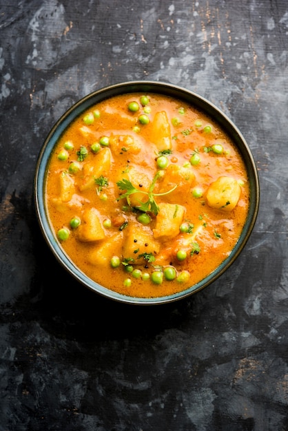 Indian Aloo Mutter curry - Potato and Peas immersed in an Onion Tomato Gravy and garnished with coriander leaves. Served in a Karahi or kadhai or pan or bowl