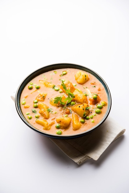 Indian Aloo Mutter curry - Potato and Peas immersed in an Onion Tomato Gravy and garnished with coriander leaves. Served in a Karahi or kadhai or pan or bowl