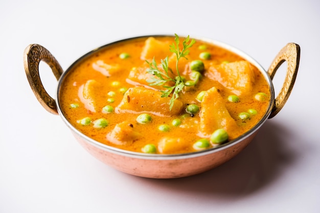 Indian Aloo Mutter 카레 - 양파 토마토 그레이비에 담근 감자와 완두콩을 고수 잎으로 장식합니다. Karahi 또는 kadhai 또는 팬 또는 그릇에 제공