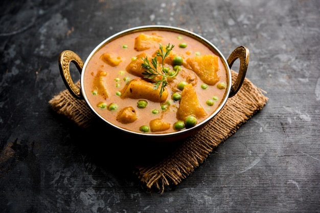Индийское карри с алоо маттер - картофель и горох, погруженные в луково-томатный соус и украшенные листьями кориандра. Подается в карахи или кадхае, на сковороде или в миске.