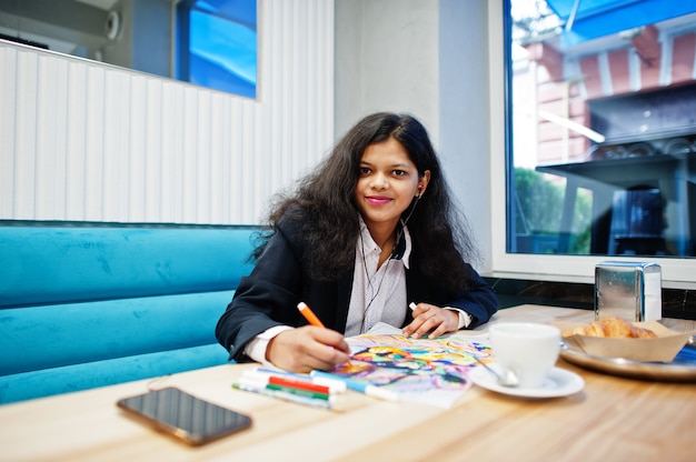 Indian artist woman wear formal paint picture and listening hindu music from earphones