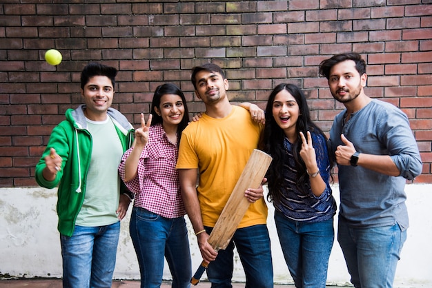 Studenti universitari asiatici indiani o amici che giocano a cricket come attività sportiva all'aperto