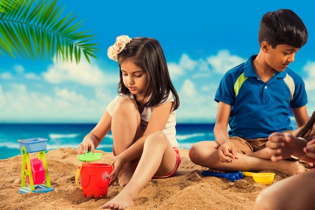 Bambini carini asiatici indiani che giocano sulla sabbia della spiaggia