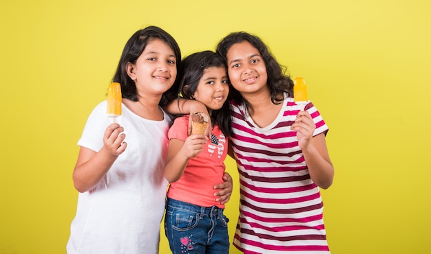 Indian or Asian cute little kids eating Ice cream or mango bar or candy. Isolated over colourful background