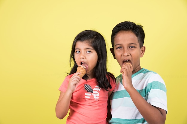 Indian or asian cute little kids eating ice cream or mango bar or candy. isolated over colourful background