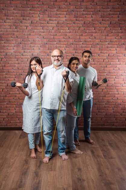 Indian asian Family exercising at home. senior Parents with young kids doing yoga, lifting weight, using theraband in living room interior. indoor workout concept