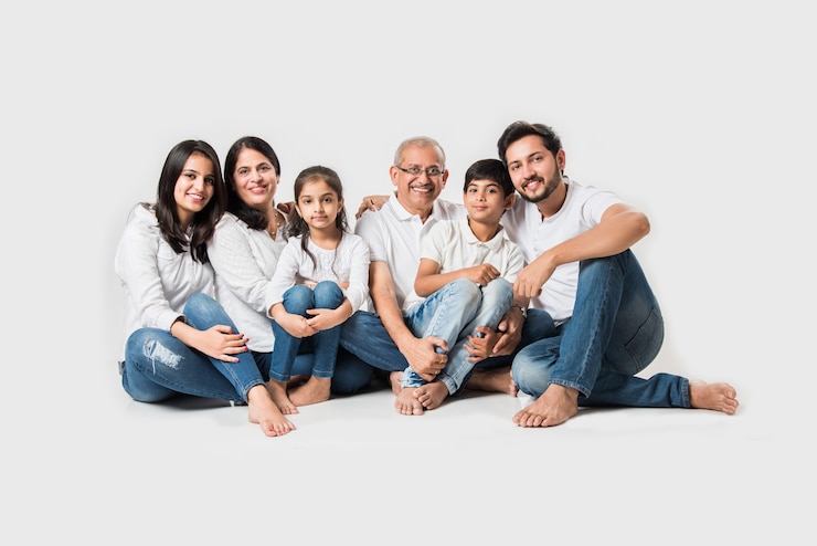 Photo indian asian family sitting over white background. senior and young couple with kids wearing white top and blue jeans. selective focus