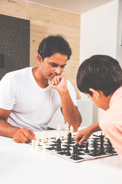 Photo indian asian father and son playing chess at home