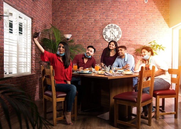 Indian asian friends Eating in Restaurant Dining Concept wearing protective face mask after corona pandemic