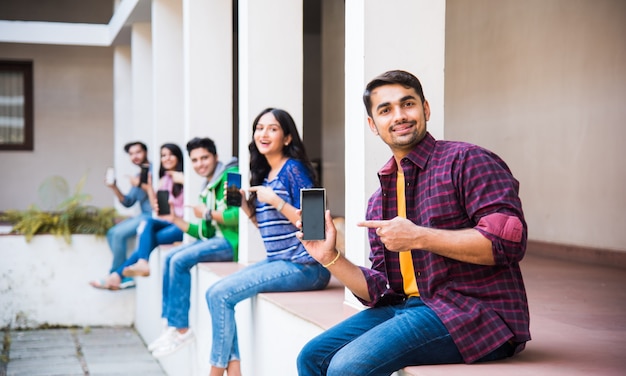 Gruppo asiatico indiano di studenti universitari che utilizzano smartphone per social media, sms, guardare video