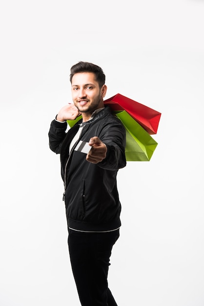 Indian asian man showing his shopping bags and credit or debit card while standing over white background