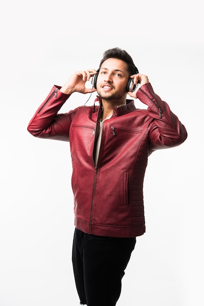 Indian asian Man with headphones while wearing leather jacket and dancing. isolated over white background