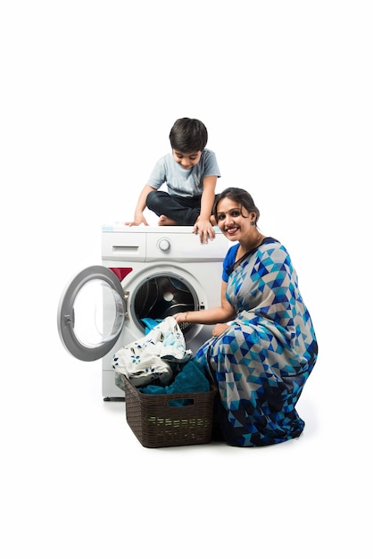 Индийская азиатская красивая домохозяйка стирает тряпки в стиральной машине и дети смотрят