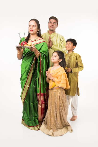 Indian Asian smart family welcoming Lord Ganesha Idol on Ganesh Festival with Pooja Thali and sweets. standing isolated over white background