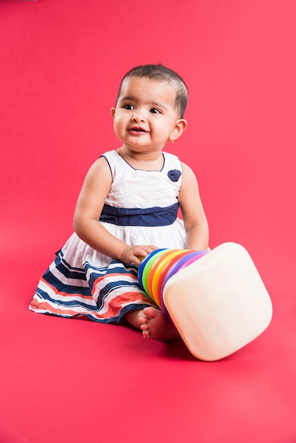 Indian or Asian Toddler, Infant or baby playing with toys or blocks while lying or sitting isolated over bright or colourful background