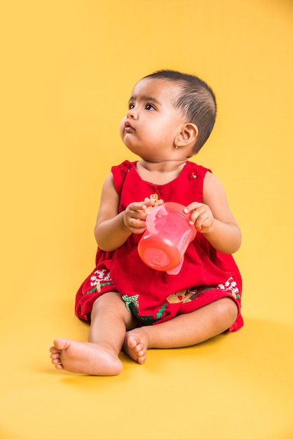 Indian or Asian Toddler, Infant or baby playing with toys or blocks while lying or sitting isolated over bright or colourful background