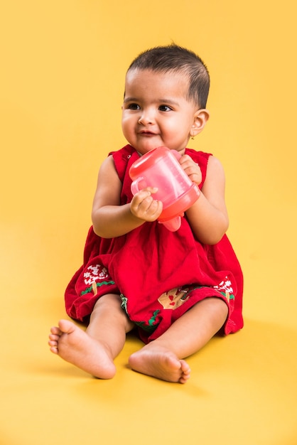 Indian or Asian Toddler, Infant or baby playing with toys or blocks while lying or sitting isolated over bright or colourful background