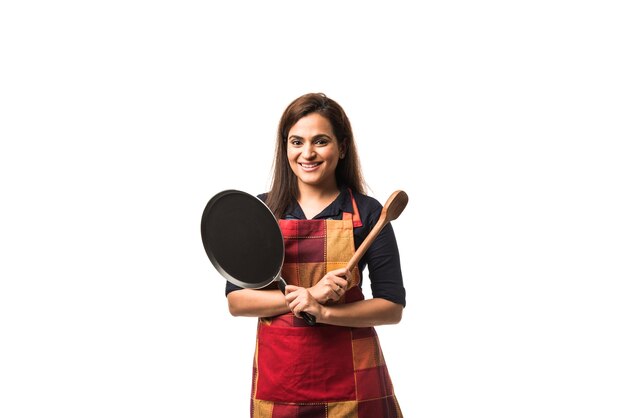 Indian or asian woman chef wearing Apron and holding Pan and spatula while standing isolated over white background