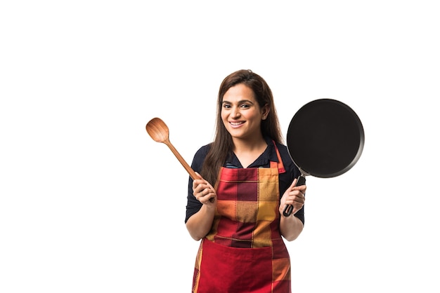 Indian or asian woman chef wearing Apron and holding Pan and spatula while standing isolated over white background