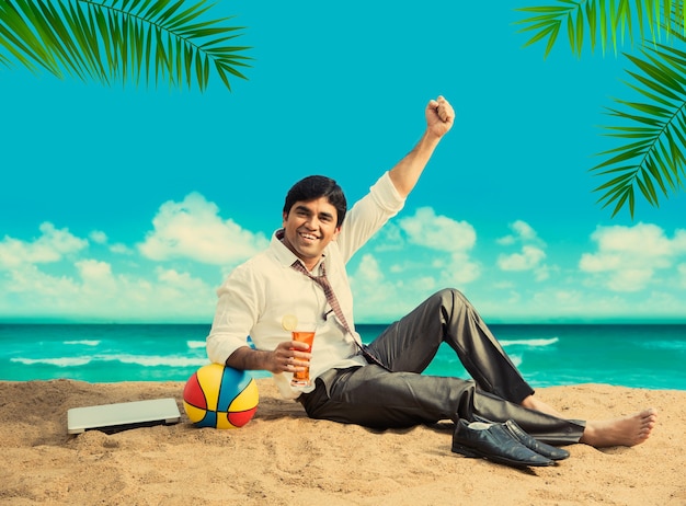 Indian Asian young businessman relaxing or working from beach enjoying break from work