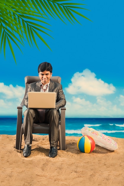 Indian Asian young businessman relaxing or working from beach enjoying break from work