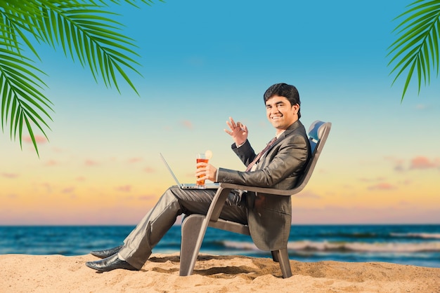 Indian Asian young businessman relaxing or working from beach enjoying break from work