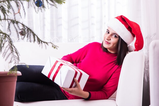 Indian Asian young family celebrating Christmas with gift while wearing Santa Hat 