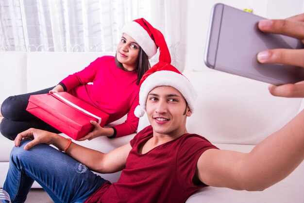 Indian Asian young family celebrating Christmas with gift while wearing Santa Hat 