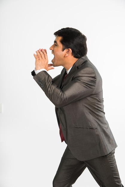 Indian asian young & handsome businessman shouting loudly in office wear standing, isolated over white background