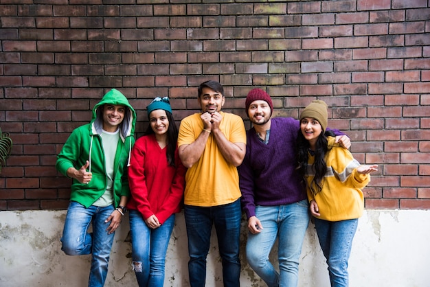 Giovani modelli o amici asiatici indiani in posa mentre indossano maglioni e cappelli di lana colorati