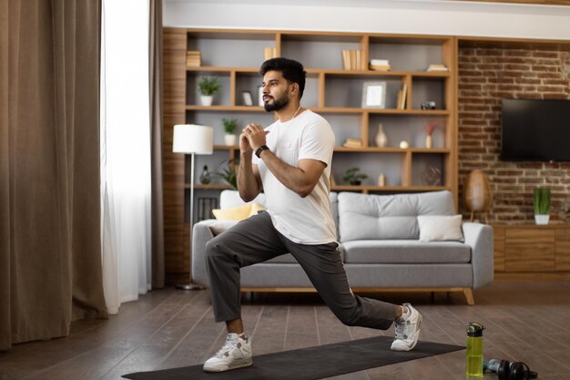 Indian athlete in sportswear doing sit ups at living room