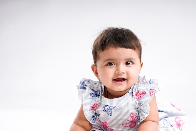 白い背景の上に座っているインドの女の赤ちゃん