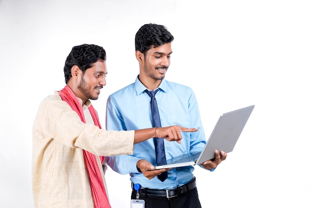 Indian bank officer or corporate government employee showing some information to farmer in laptop.