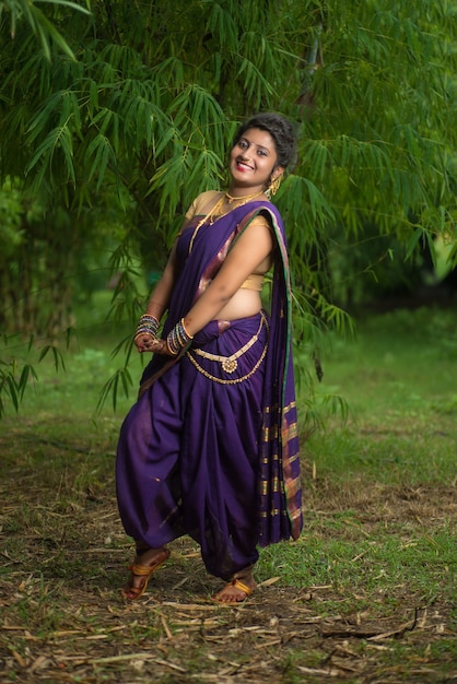 Индийская красивая молодая девушка в традиционном сари позирует на открытом воздухе