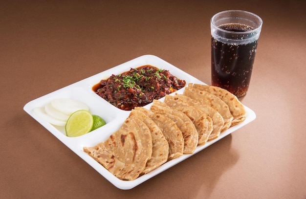 Indian Bhuna Mutton or Gosht  or lamb curry served with Roti or Chapati in white plate over colourful background