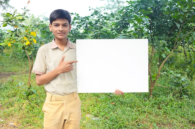 制服を着て段ボールを見せているインドの少年