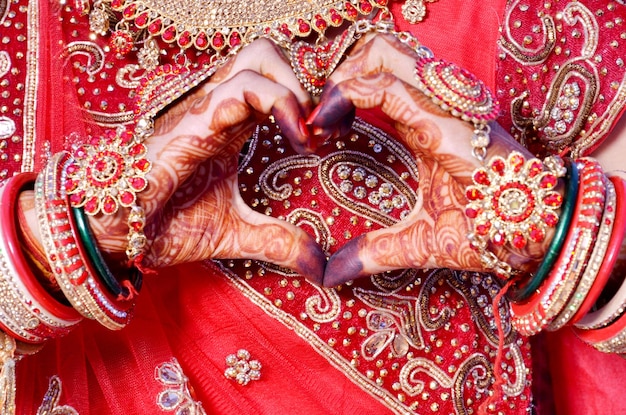 Sposa indiana che fa l'amplificatore a forma di cuore che mostra le arti mehndi