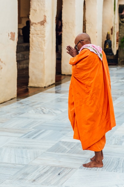 Indian Buddhist monk standing and praying on bare foot in Mahabodhi Temple 