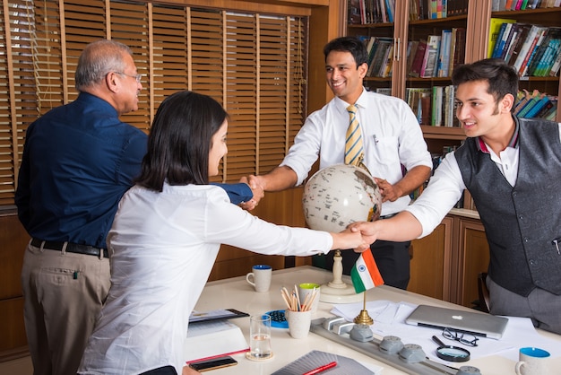 Foto indian business people nella cultura aziendale lavorando in ufficio si stringono la mano per concludere un affare