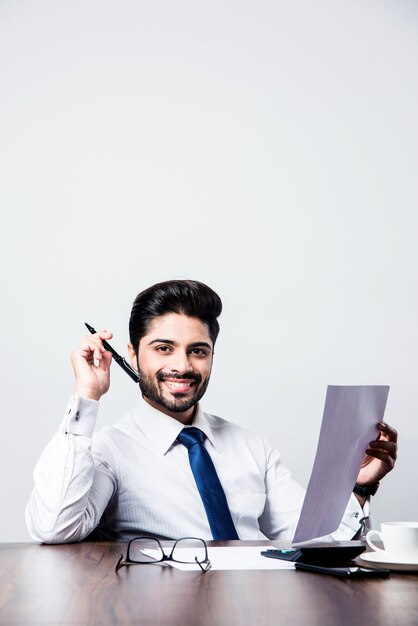 Indian businessman writing a document while sitting at desk or work station