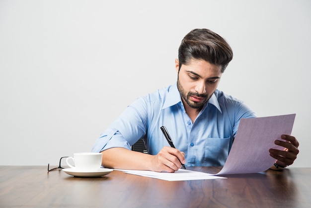 Индийский бизнесмен, писать документ, сидя за столом или на рабочем месте