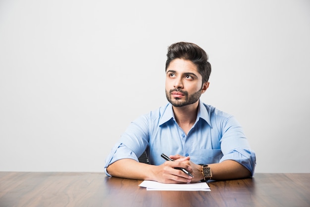 Индийский бизнесмен, писать документ, сидя за столом или на рабочем месте