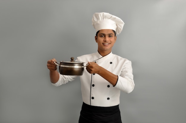 Indian chef smiling and holding pot in his hands