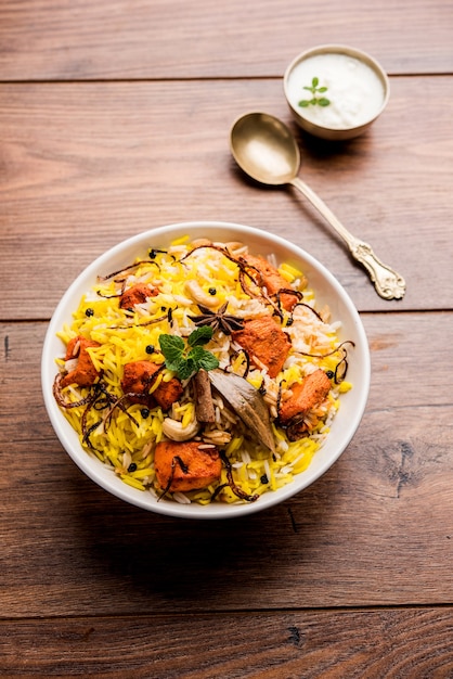 Indian Chicken Tikka Biriyani served in a bowl with yogurt. selective focus