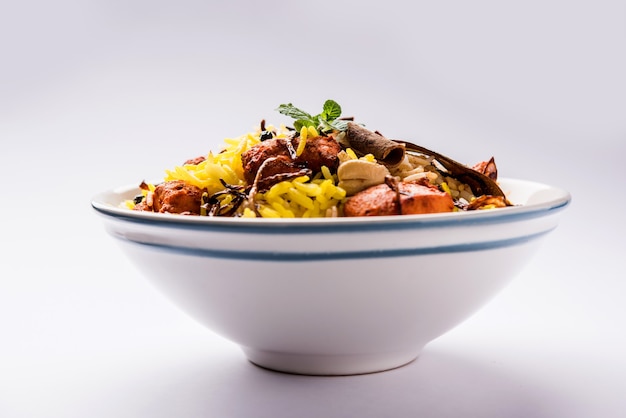 Indian Chicken Tikka Biriyani served in a bowl with yogurt. selective focus