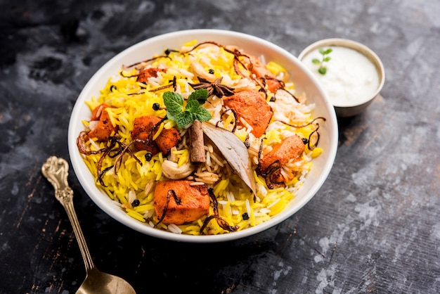 Indian Chicken Tikka Biriyani served in a bowl with yogurt. selective focus