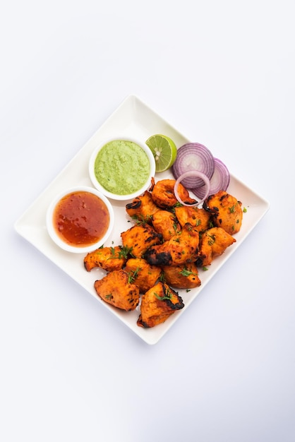 Indian chicken tikka kebabs, marinated in spices and yogurt and roasted in tandoor. served with green chutney and onion. selective focus